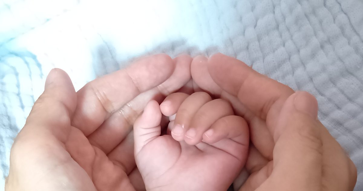 大人の手に包まれた赤ちゃんの手